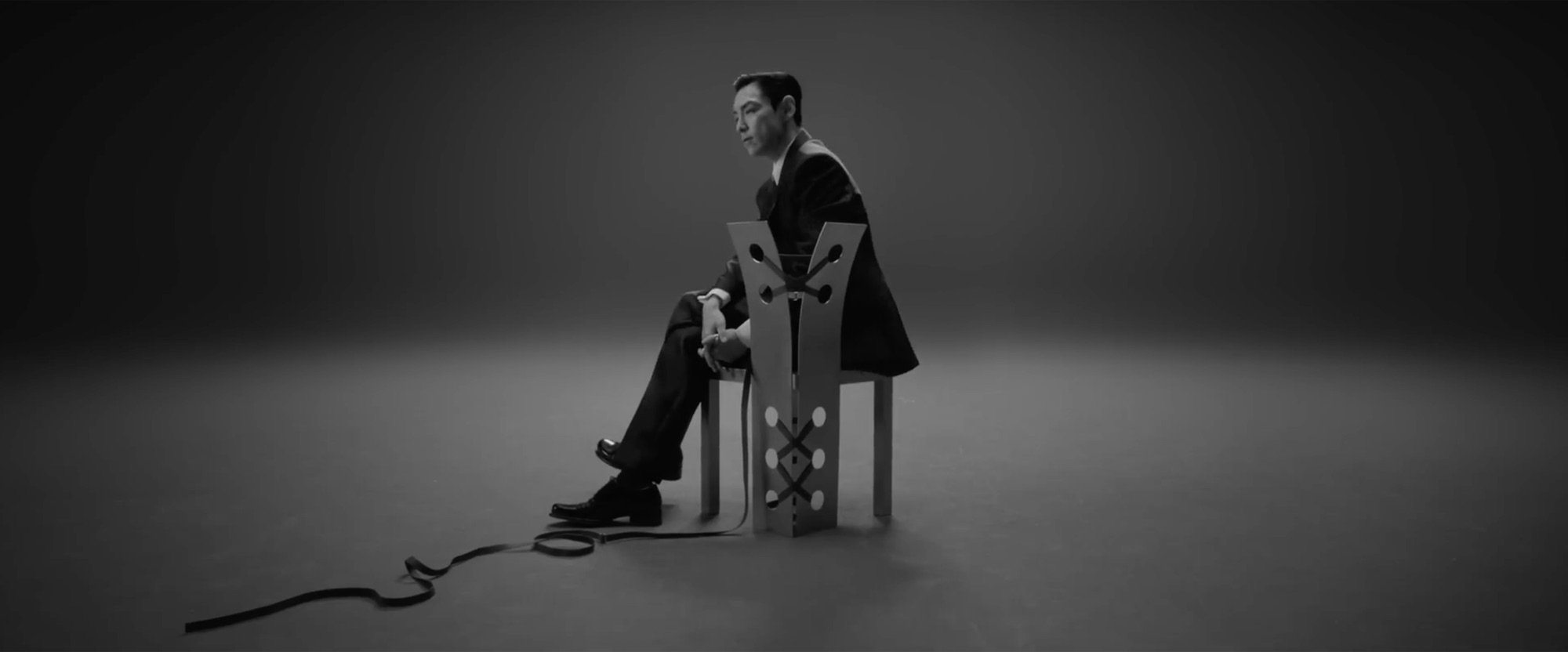 T.O.P 〈Desperado〉 뮤직비디오 스틸, 회색 스튜디오 의자에 앉은 인물
